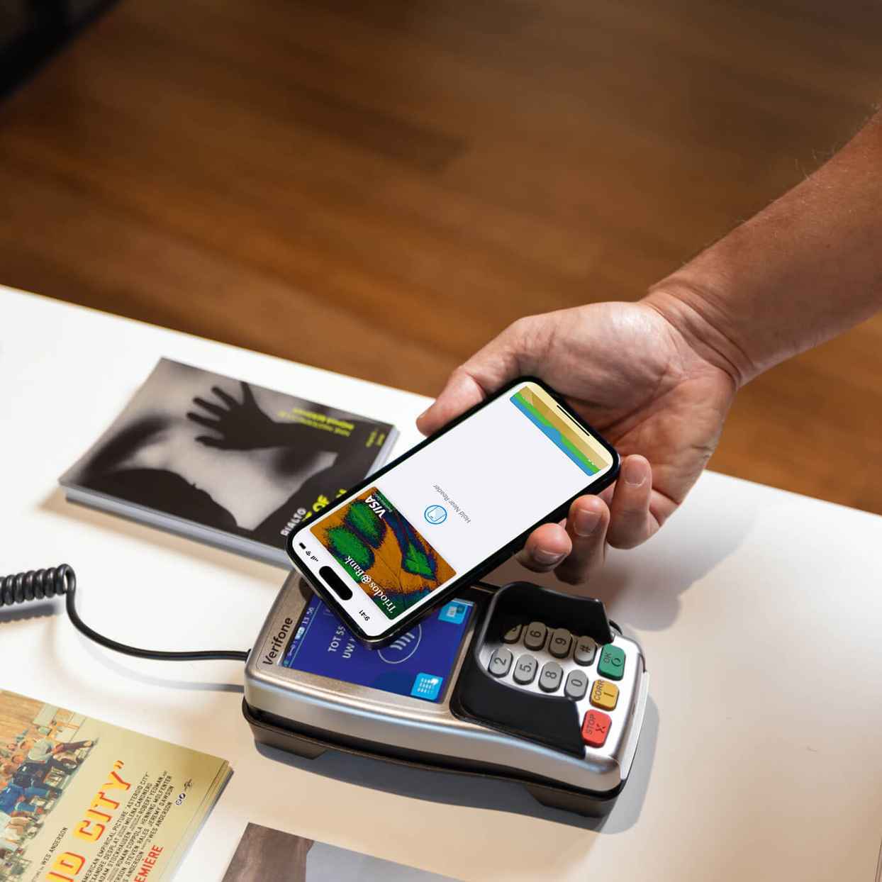 Een persoon doet een Apple Pay-betaling door een mobiele telefoon tegen een betaalautomaat te houden.