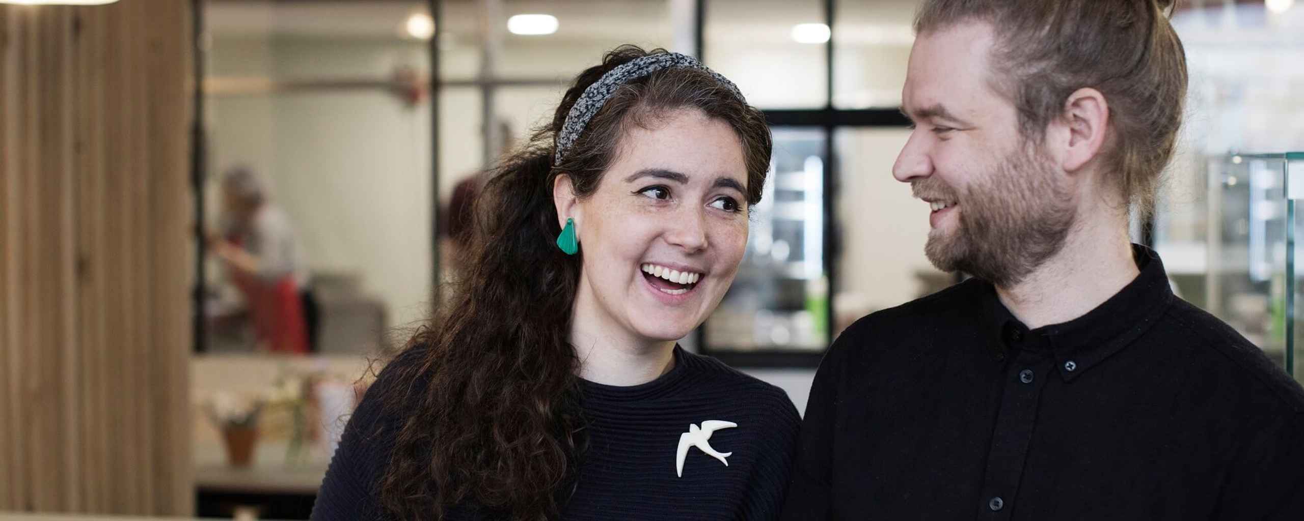 Close-up van een man en een vrouw die binnen in een lichte ruimte staan.