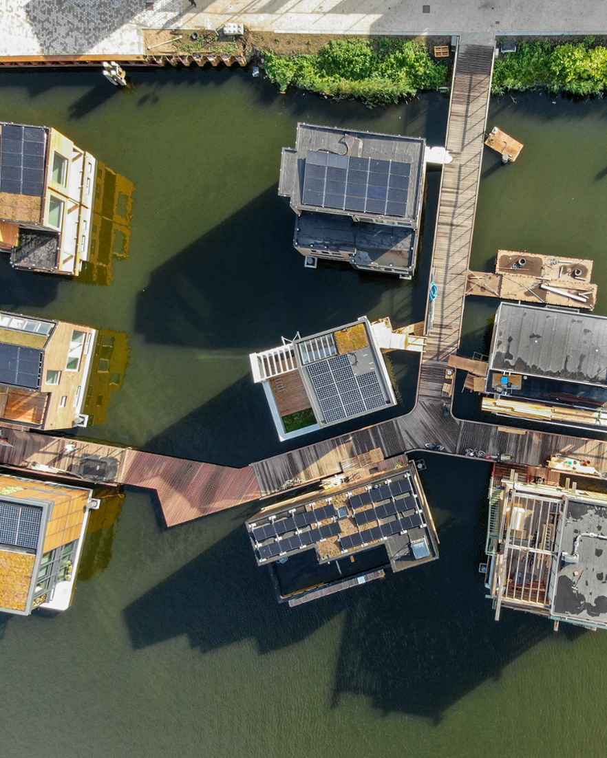 Luchtfoto van woonboten. Houten steigers verbinden de huizen met elkaar.