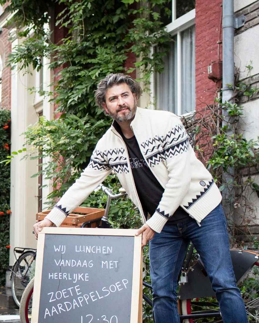 Man plaatst een a-bord over de lunchkaart buiten voor zijn restaurant in een stadsomgeving.