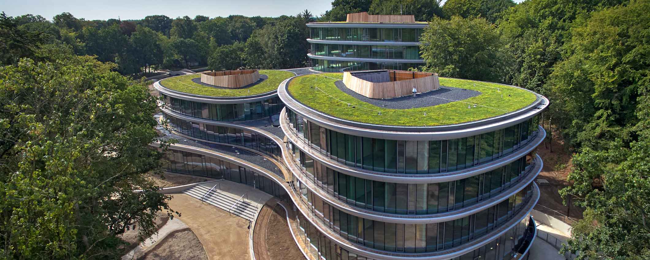 Het kantoor van Triodos Bank, de Reehorst, staat midden in het groen. Het gebouw heeft ronde vormen, veel glasen daken met planten.