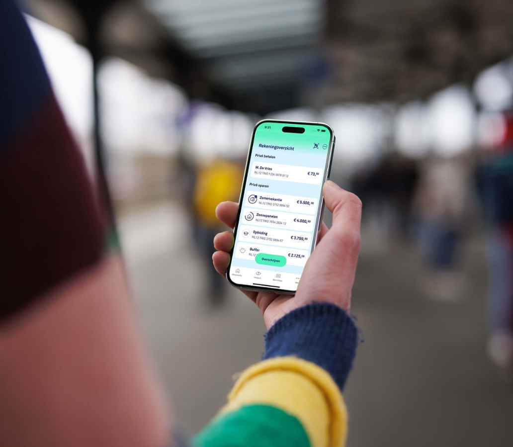 Persoon houdt met één hand een mobiele telefoon vast met daarop een overzicht van spaardoelen.