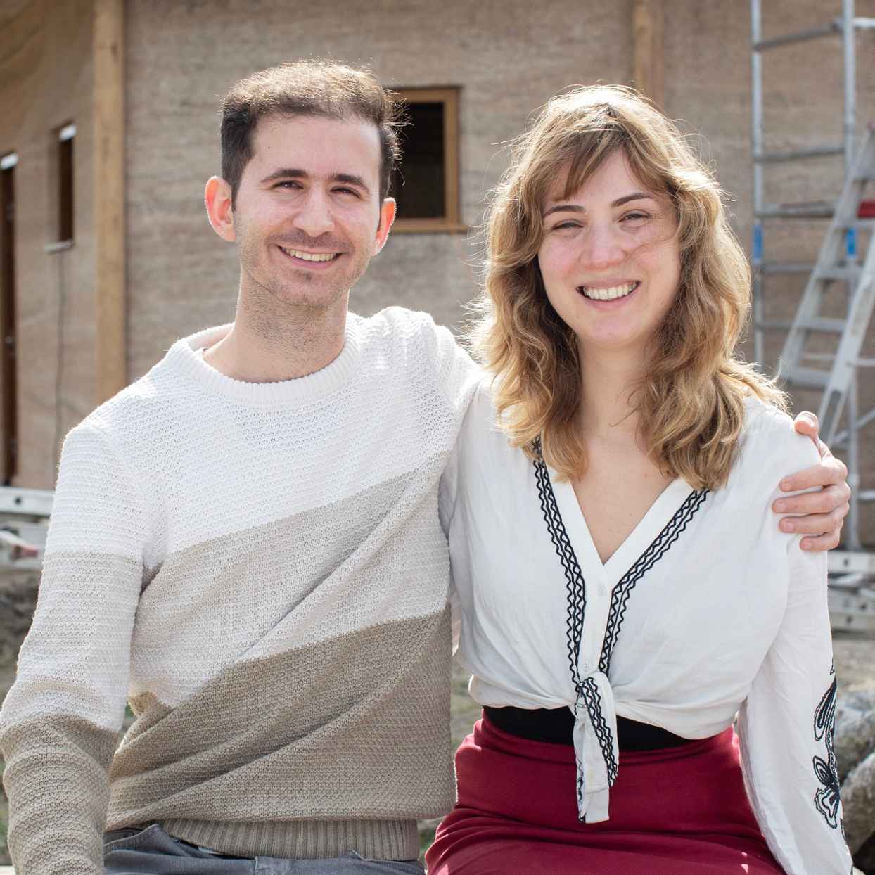 Man en een vrouw zitten dicht bij elkaar voor een huis in aanbouw.