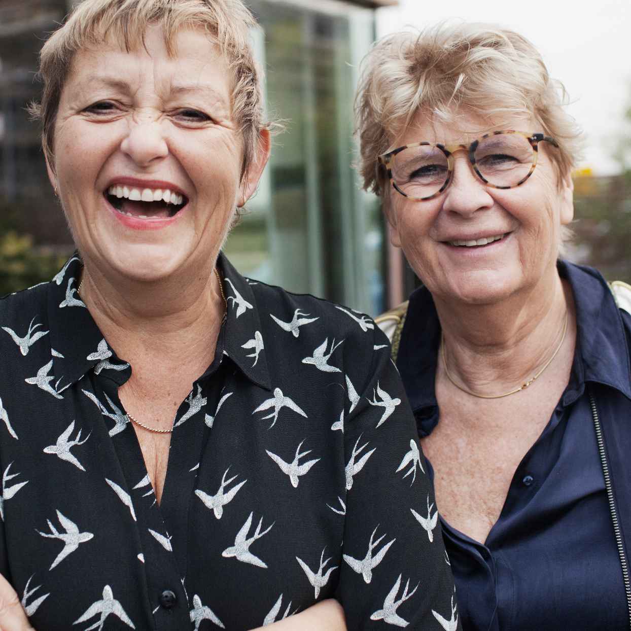 Close-up van twee vrouwen die naast elkaar staan voor een gebouw.
