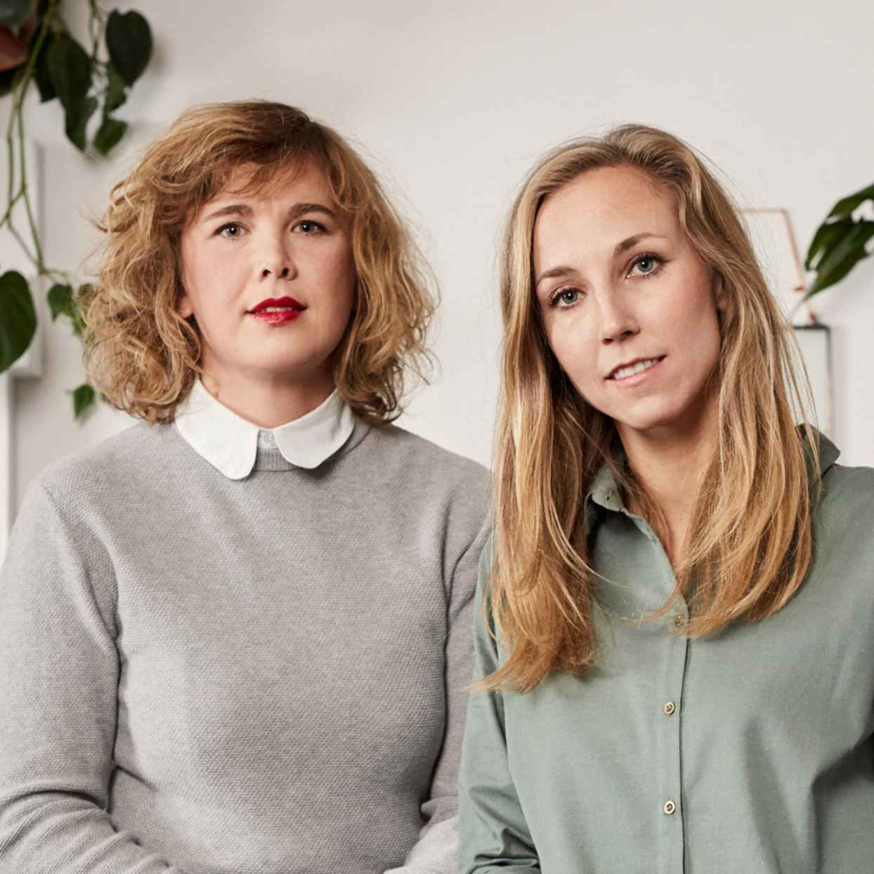 Close-up van twee vrouwen in een neutrale ruimte met planten. Zij zijn de eigenaren van het modemerk CharlieMary en klant van Triodos Bank.